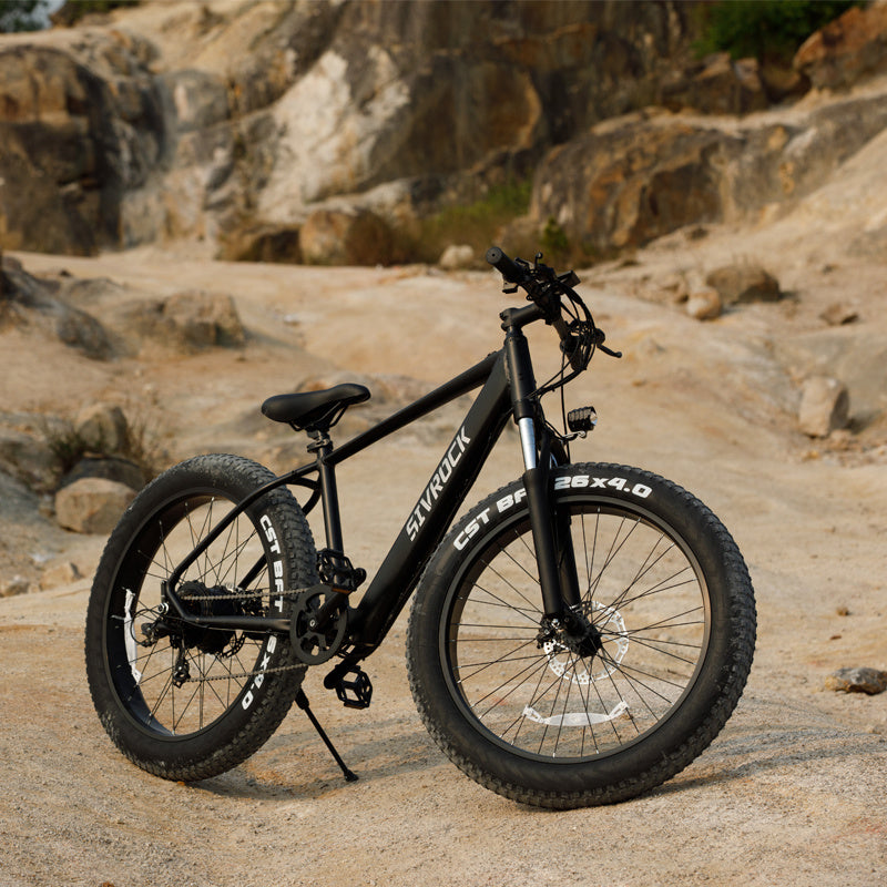 I Got It First 1000W electric fat tire bike in black with rugged tires on rocky terrain